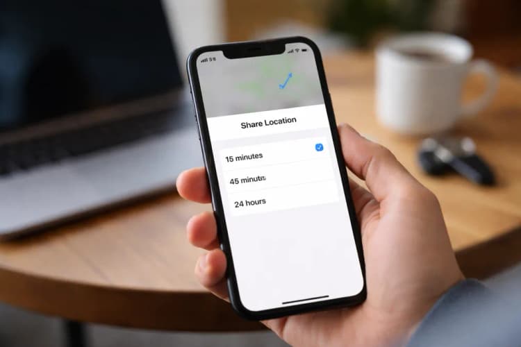 Ilustrasi layar iPhone menampilkan slider durasi berbagi lokasi di aplikasi Find My, dengan opsi '15 menit', '45 menit', dan '24 jam' terlihat jelas